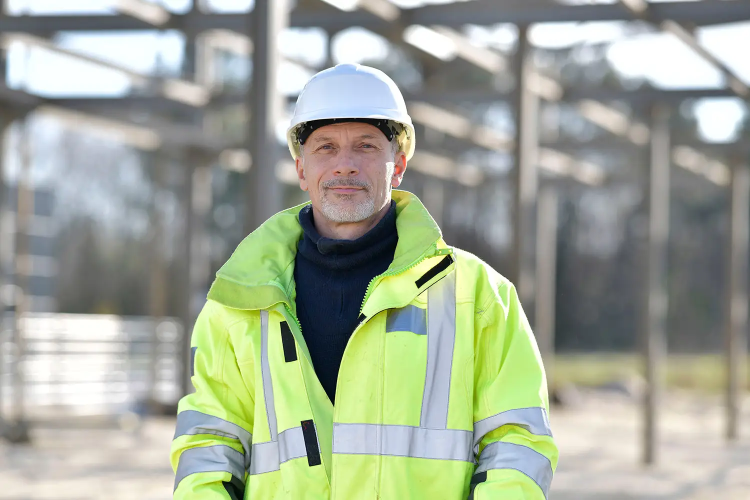 Bauleiter mit Sicherheitsweste steht vor einer Baustelle